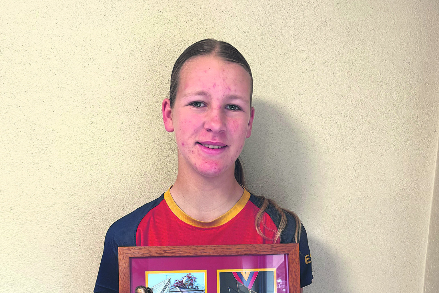 Ruby Thomas proudly shows off her three best-and-fairest awards she won in 2025.