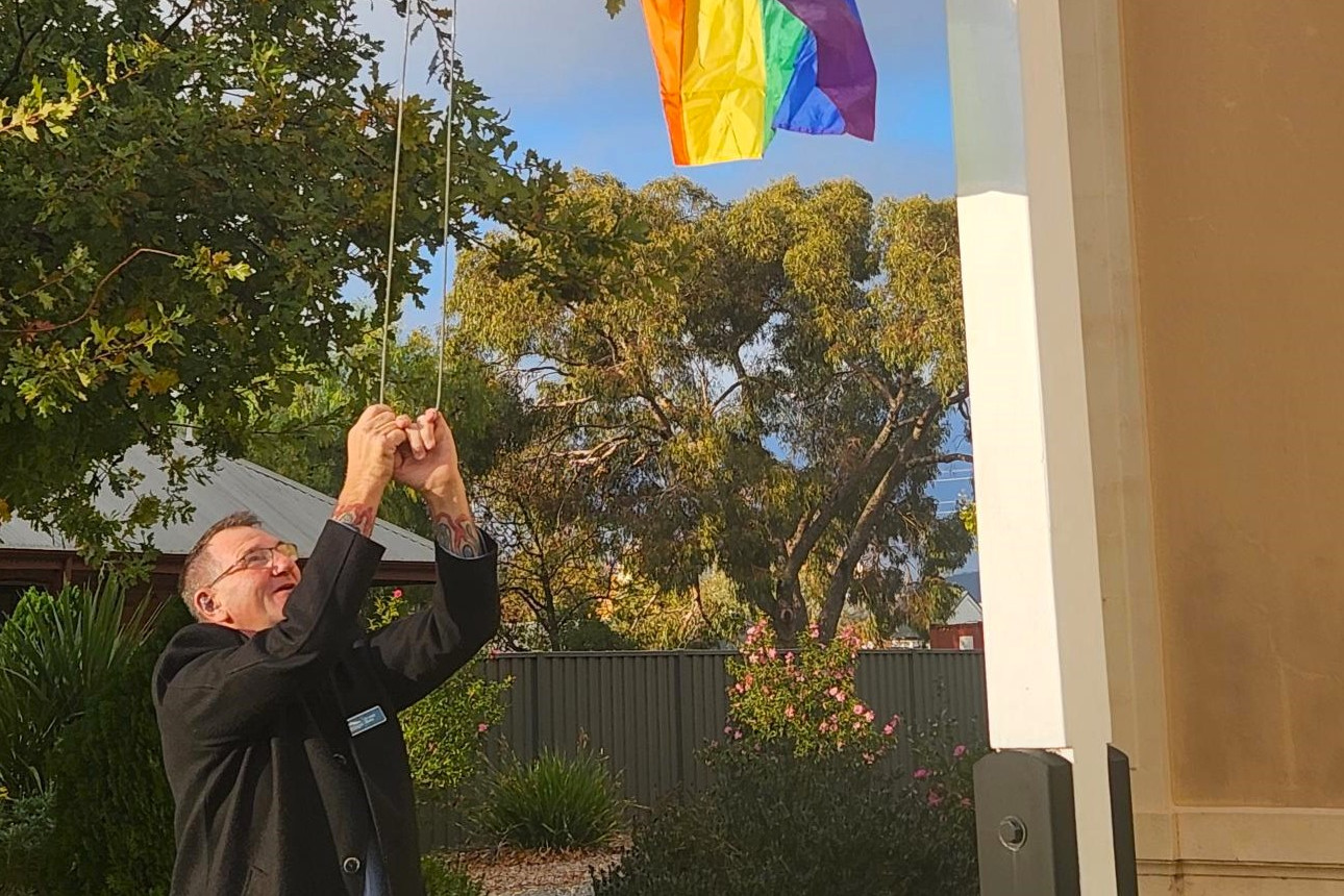 Cr Jack Blake raises the rainbow flag at the council chambers on Saturday in support of IDAHOBIT Day.