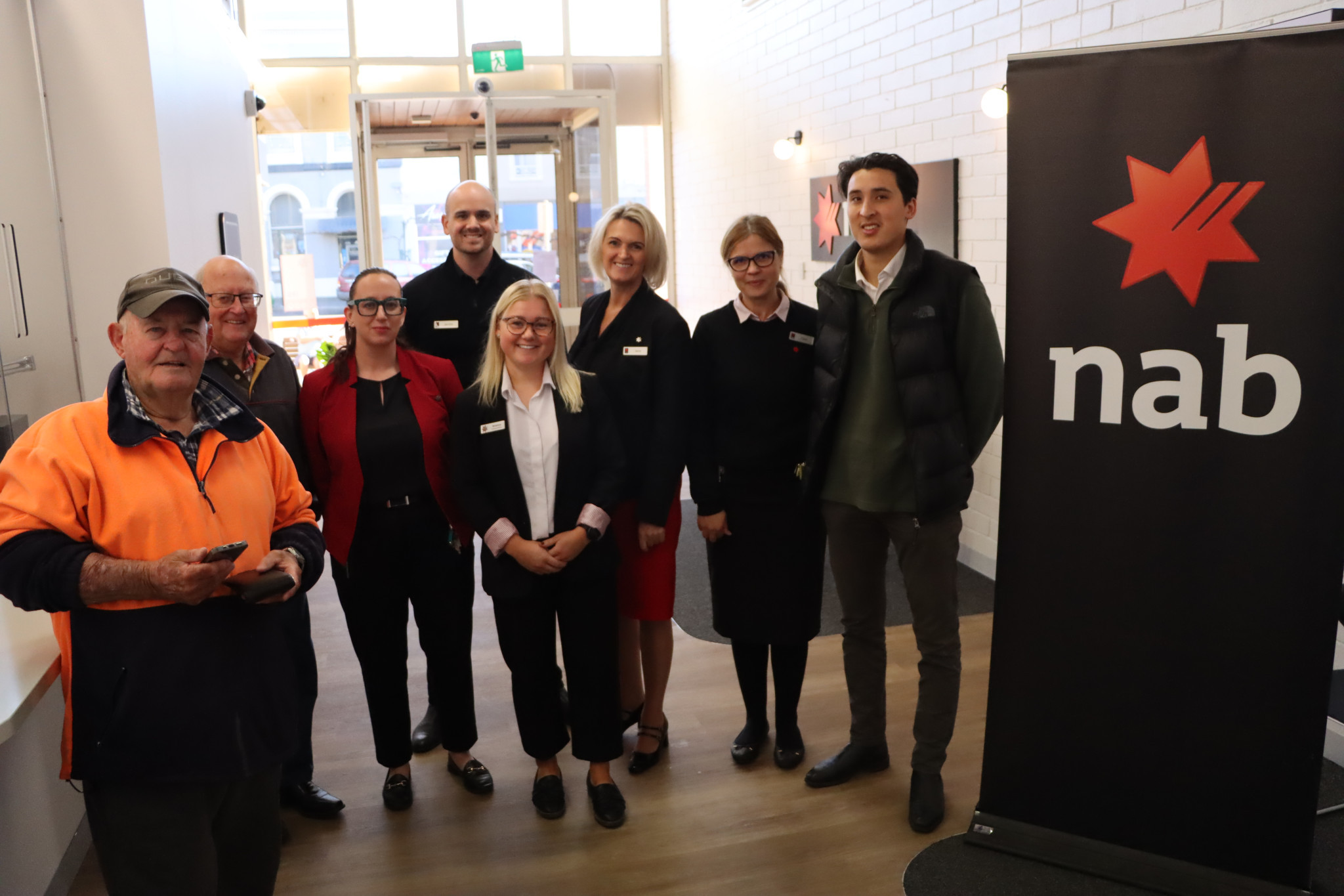 National Australia Bank customers Peter and Alan with team members Stephanie, Jarrod, Brianna, Jane Lincoln, Cate and Shu at the newly renovated branch in Barkly Street.